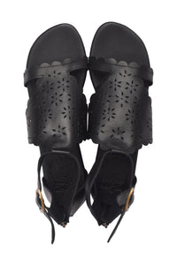 A pair of black leather slide sandals with floral laser-cutout details on the straps and scalloped edges, shown from a top-down view on a white background.