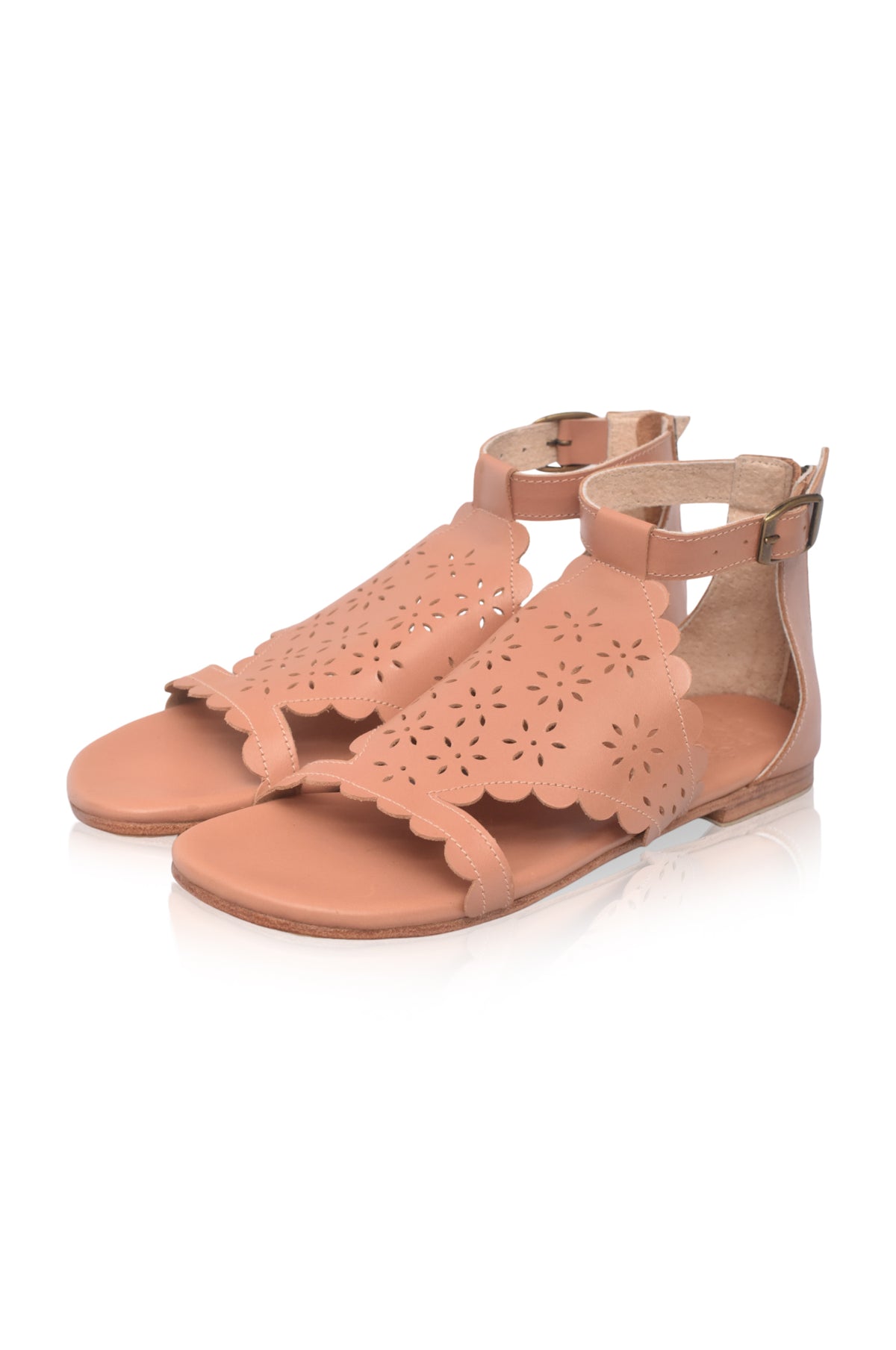 A pair of women's flat sandals in a warm tan or nude color, featuring scalloped laser-cut straps and adjustable ankle buckles, shown on a white background.