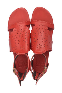 A pair of red leather flat sandals with scalloped edges and laser-cut floral patterns on the straps, shown from a top-down view on a white background.