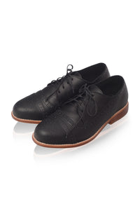 A pair of black leather lace-up oxford shoes with brogue detailing and a brown sole, displayed on a clean white background.