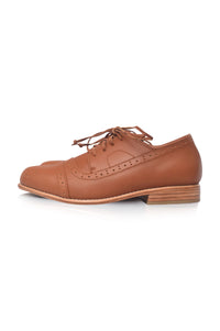 A single brown leather cap-toe oxford shoe with brogue detailing and a stacked wood-look heel, shown from a side profile on a white background.