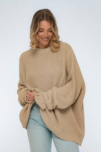 Woman wearing a beige knit sweater on a white background