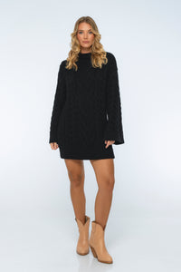 Woman wearing a black dress and beige boots on a white background