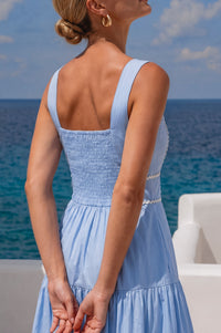 Woman in a light blue dress standing by the ocean