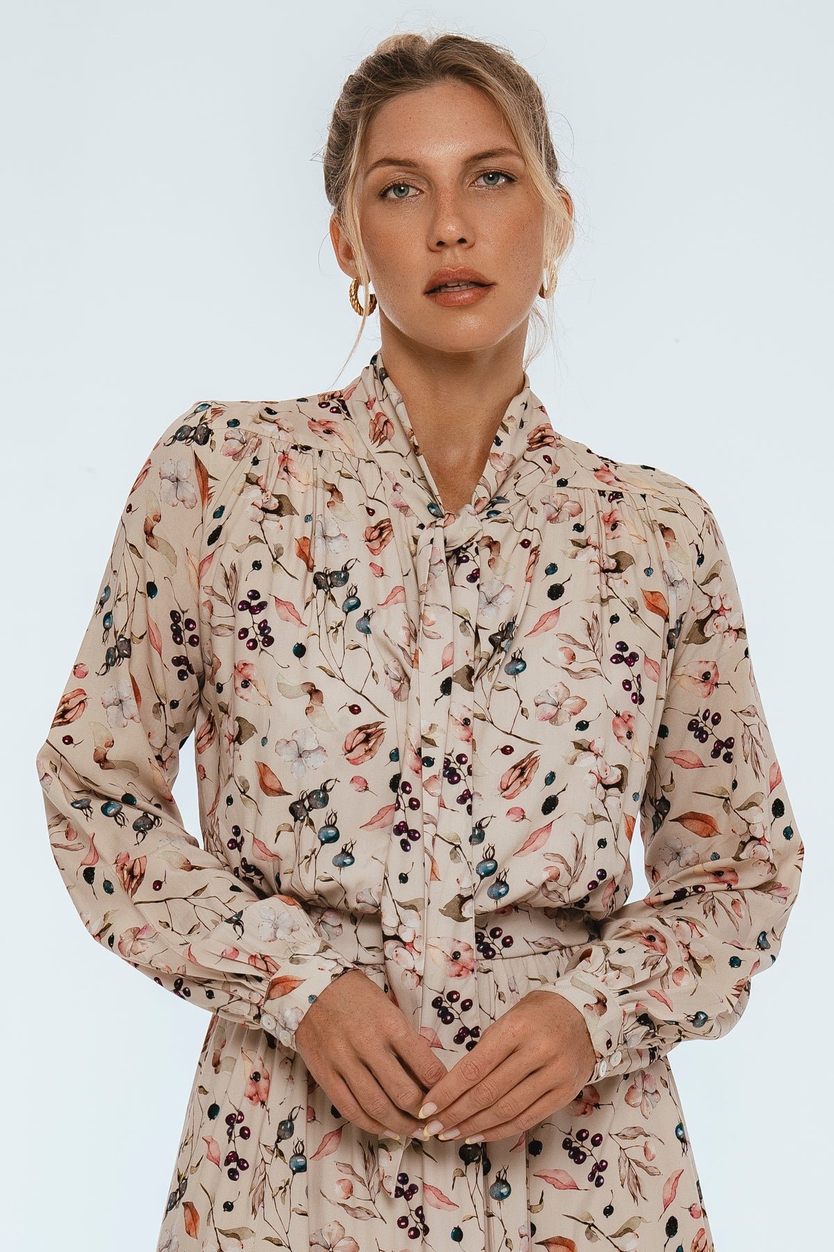 Woman wearing a floral patterned blouse against a white background