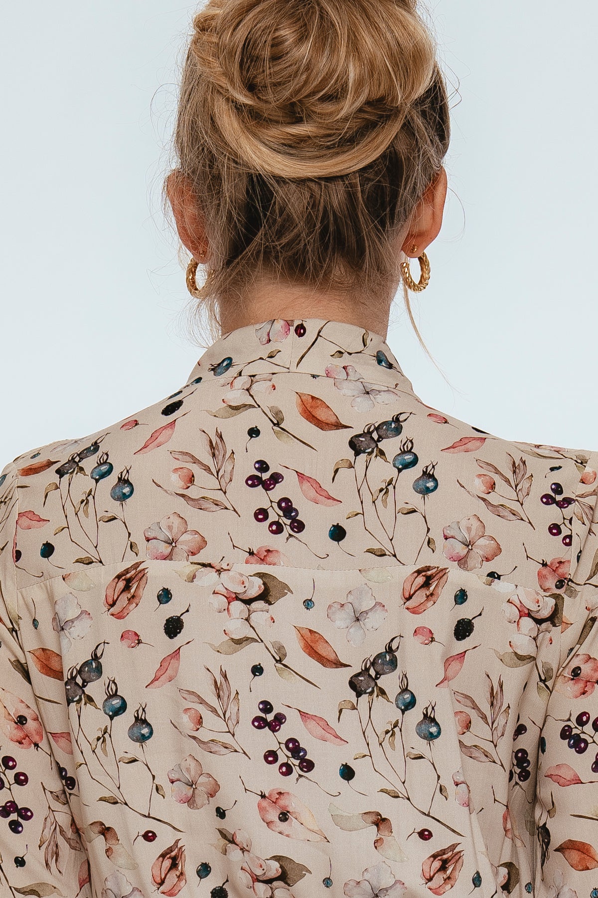Back view of a person wearing a floral patterned blouse against a white background