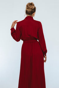 Person wearing a long red dress against a white background