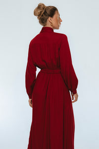Woman wearing a long red dress against a white background