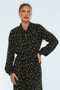 Woman wearing a black floral dress against a white background