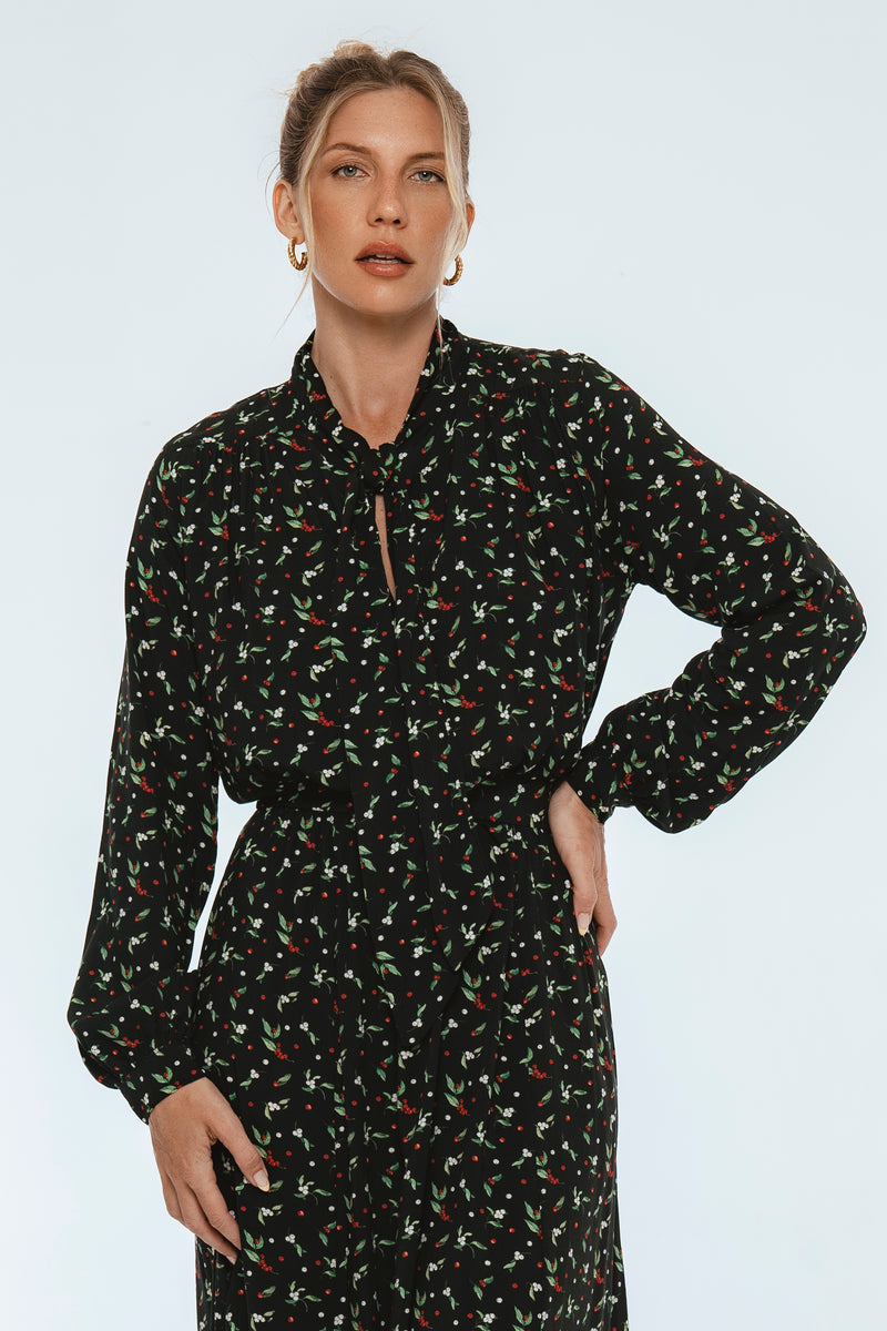 Woman wearing a black floral dress against a white background