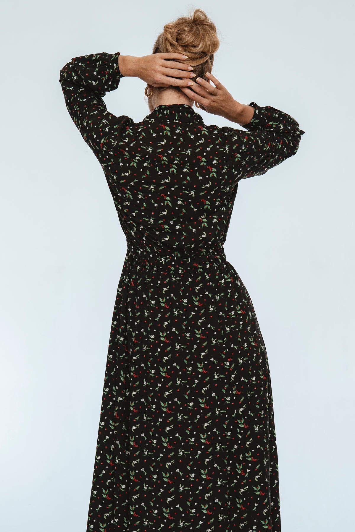 Woman wearing a black floral dress against a white background