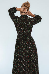 Woman wearing a black floral dress against a white background