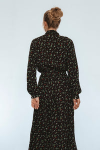 Person wearing a black floral dress against a white background