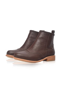 A pair of dark brown leather ankle boots with a low stacked heel and a light tan sole, shown on a clean white background with a soft reflection.