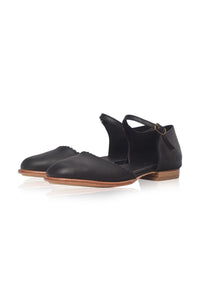 Brown flat shoe with strap details on a white background