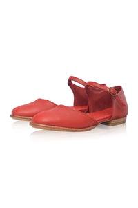 A pair of red leather flat sandals with ankle straps and a small gold-tone buckle, displayed on a clean white background.