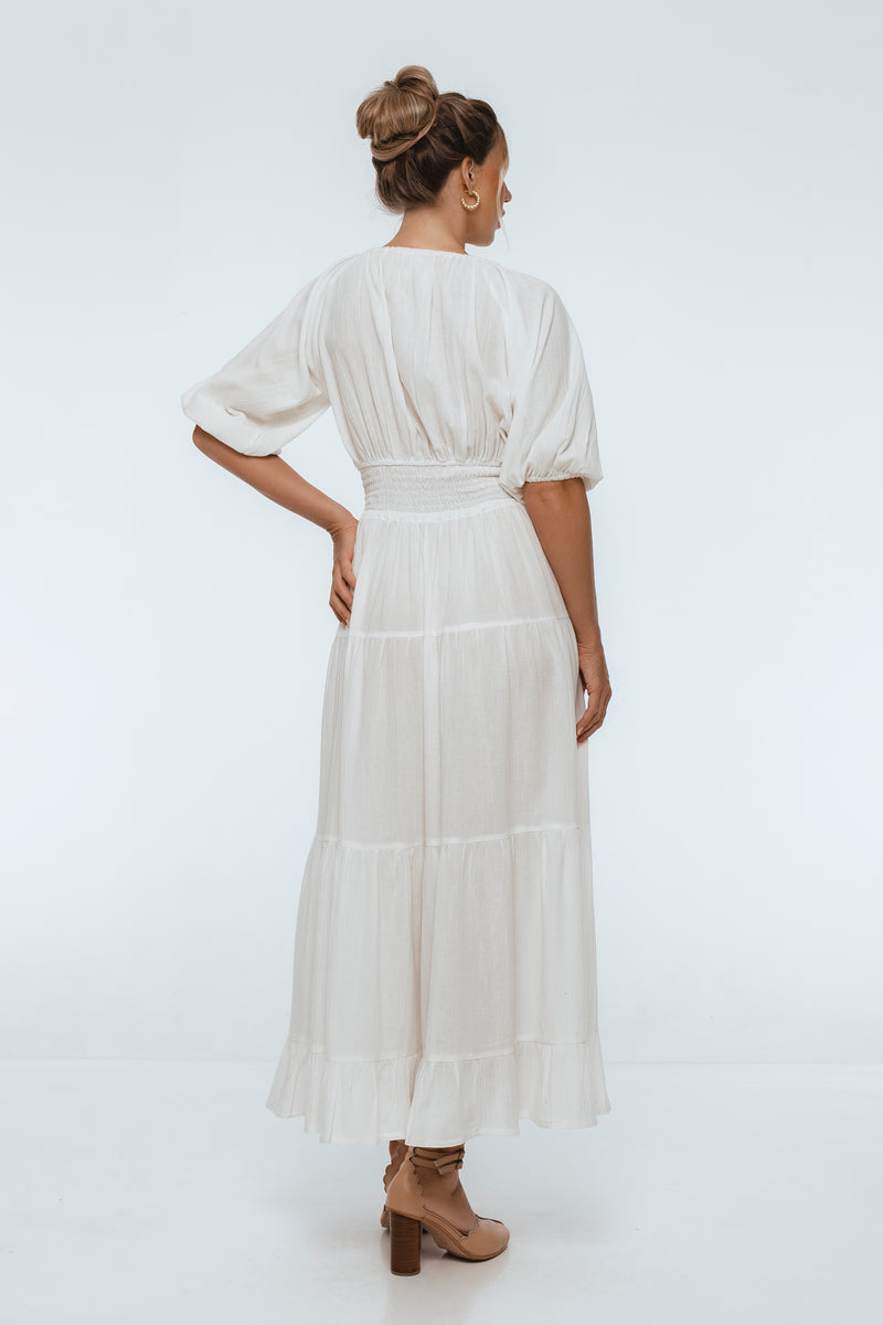 Woman wearing a white dress with sheer sleeves on a white background