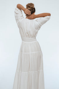 Woman wearing a white dress with a plain background