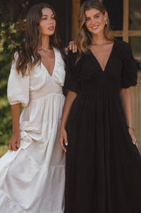 Two women wearing elegant dresses standing outdoors.
