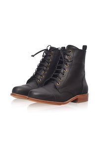 A pair of black leather lace-up combat boots with gold-tone eyelets and a brown stacked sole, shown on a clean white background.