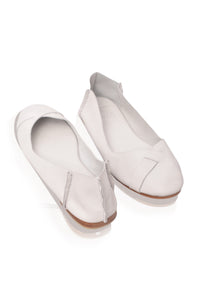 A pair of off-white leather slip-on flats with a pointed toe and decorative stitching, displayed on a clean white background.