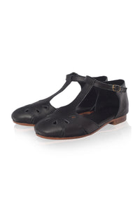 A pair of black leather T-strap flat sandals with cutout details on the toe, shown on a clean white background.