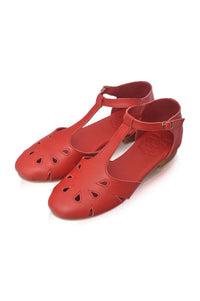 A pair of red leather T-strap flat shoes with decorative cutouts on the toe, displayed on a clean white background.