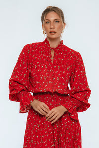 Woman wearing a red floral dress against a light gray background