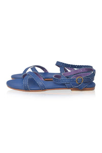 A pair of blue leather flat sandals with braided straps, a back strap with a buckle, and a purple glittery insole, shown against a white background.