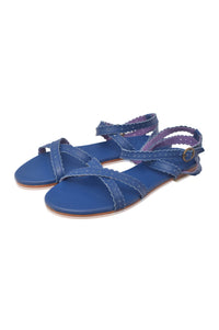 A pair of blue flat sandals with braided crisscross straps and adjustable ankle straps, shown on a plain white background.