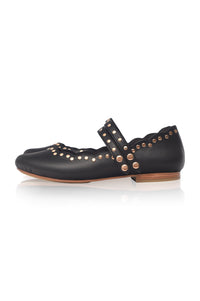 Black flat shoe with gold studs and buckles on a white background