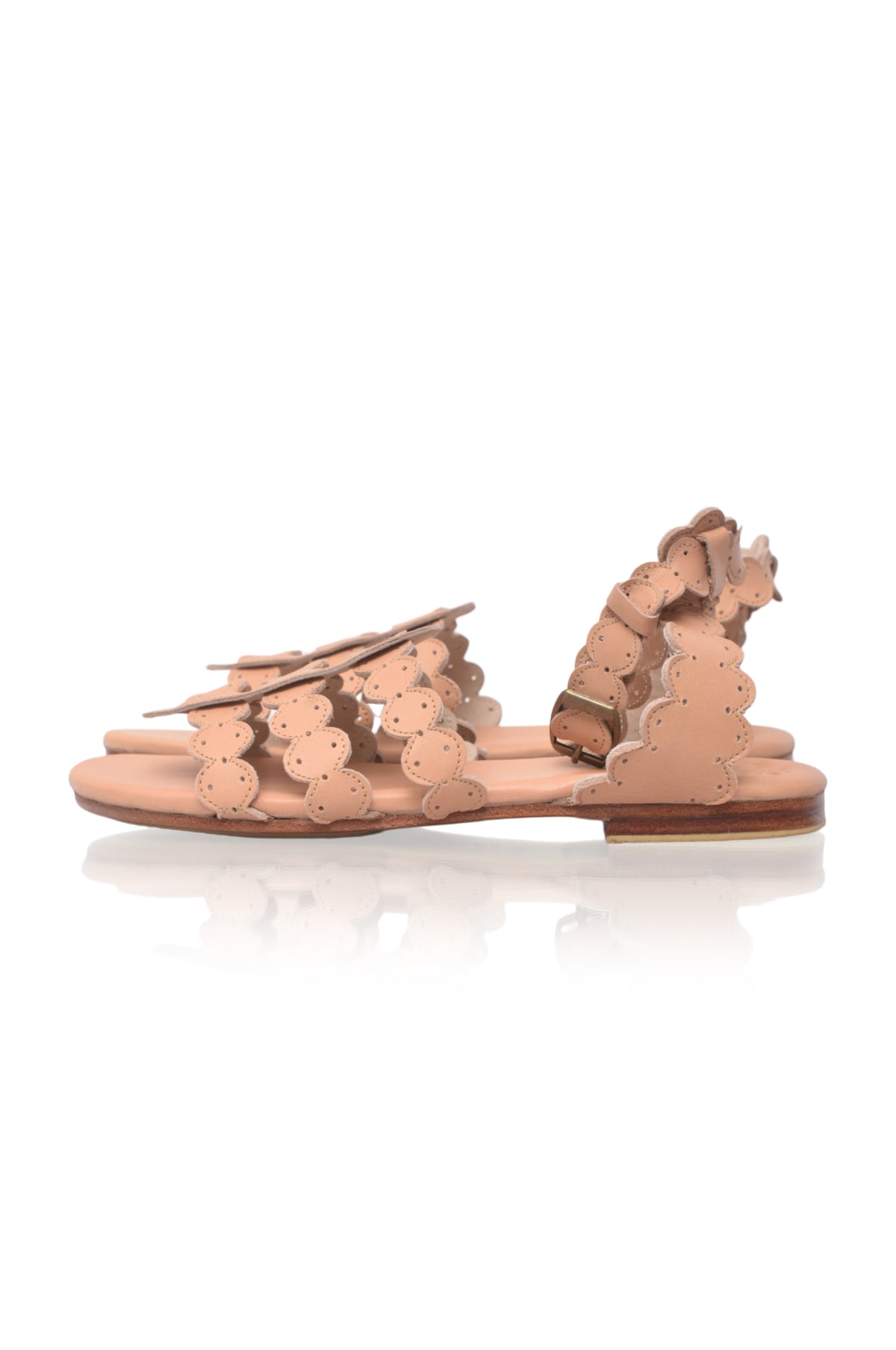 Pair of beige sandals with floral details on a white background