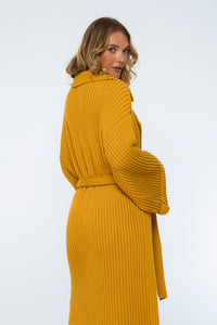 Woman wearing a mustard yellow knitted coat on a white background